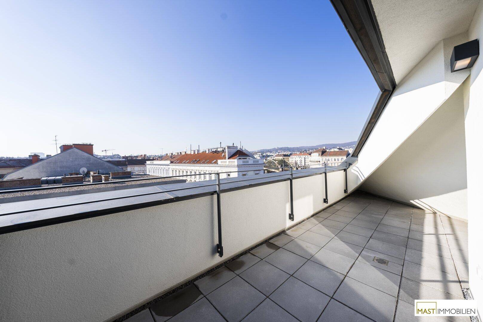 Geräumige Dachterrasse mit Fliesenboden und Blick über die Dächer der Stadt.