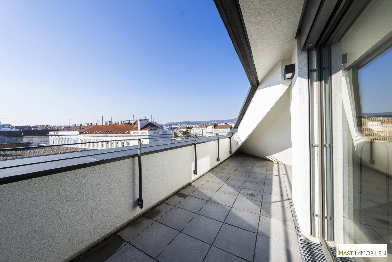 Sonnige Dachterrasse mit Fliesenboden und weitem Blick über die städtische Umgebung.