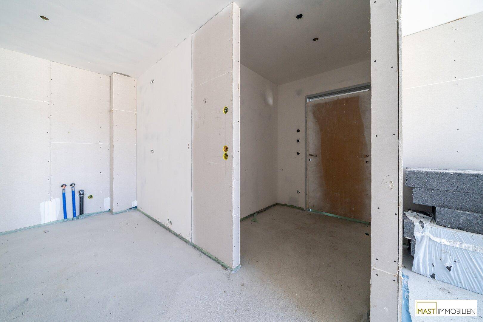 Unfertiger Innenraum mit Trockenbauwänden und Baumaterialien, bereit für den weiteren Ausbau.