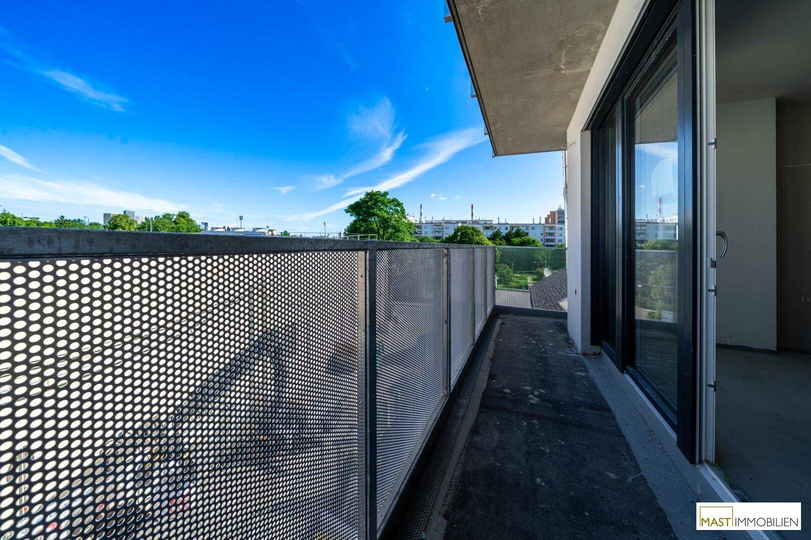 Langer Balkon mit moderner Metallbrüstung und Blick auf die umliegende Bebauung und Bäume.
