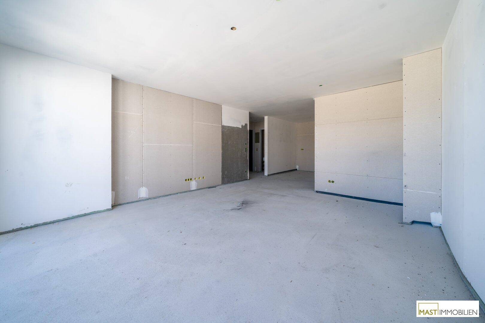 Großer, unfertiger Raum mit Trockenbauwänden und Betonboden, bereit für den weiteren Ausbau.