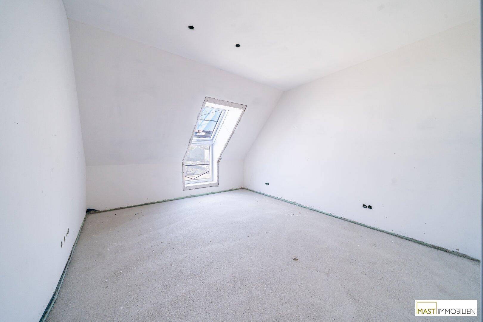 Heller Dachraum im Rohbau mit schräger Decke und einem Dachfenster, bereit zum Ausbau.