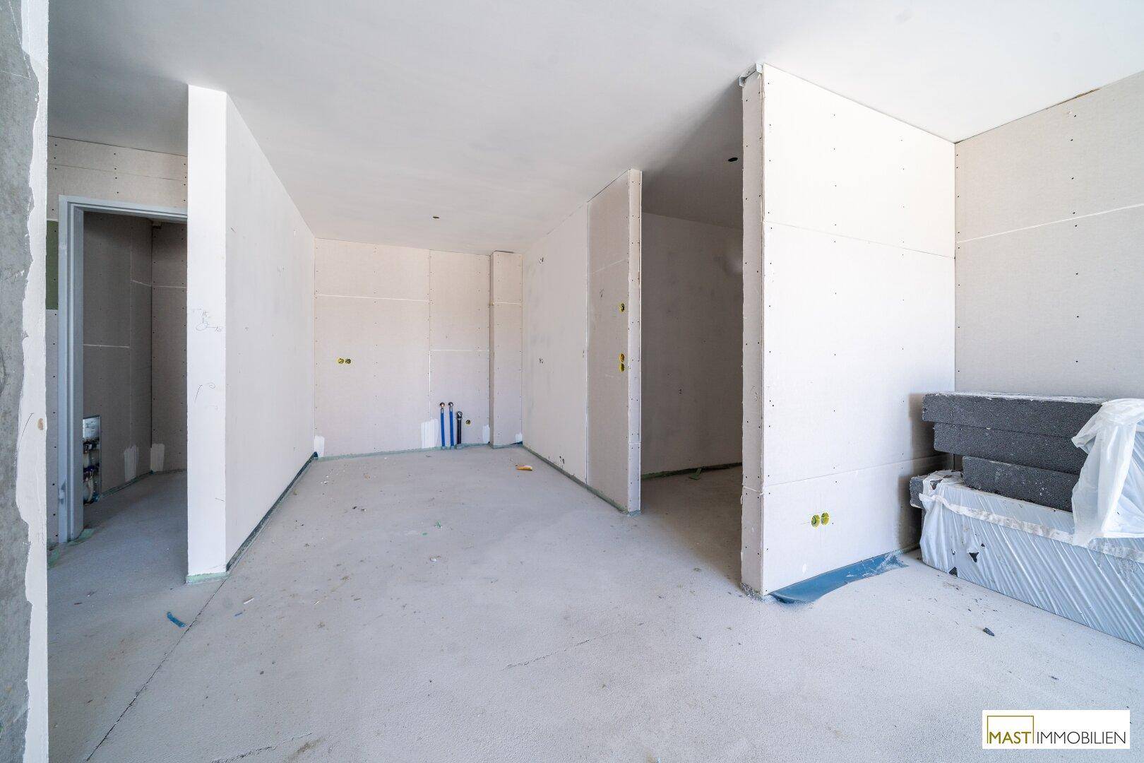 Unfertiger Raum mit sichtbaren Sanitäranschlüssen, bereit für die Installation von Küche oder Bad.