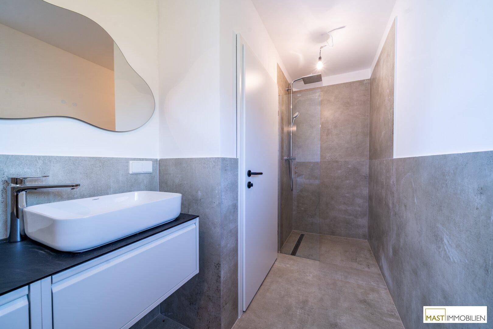 Modernes Badezimmer mit elegantem Waschtisch und geräumiger, ebenerdiger Dusche.