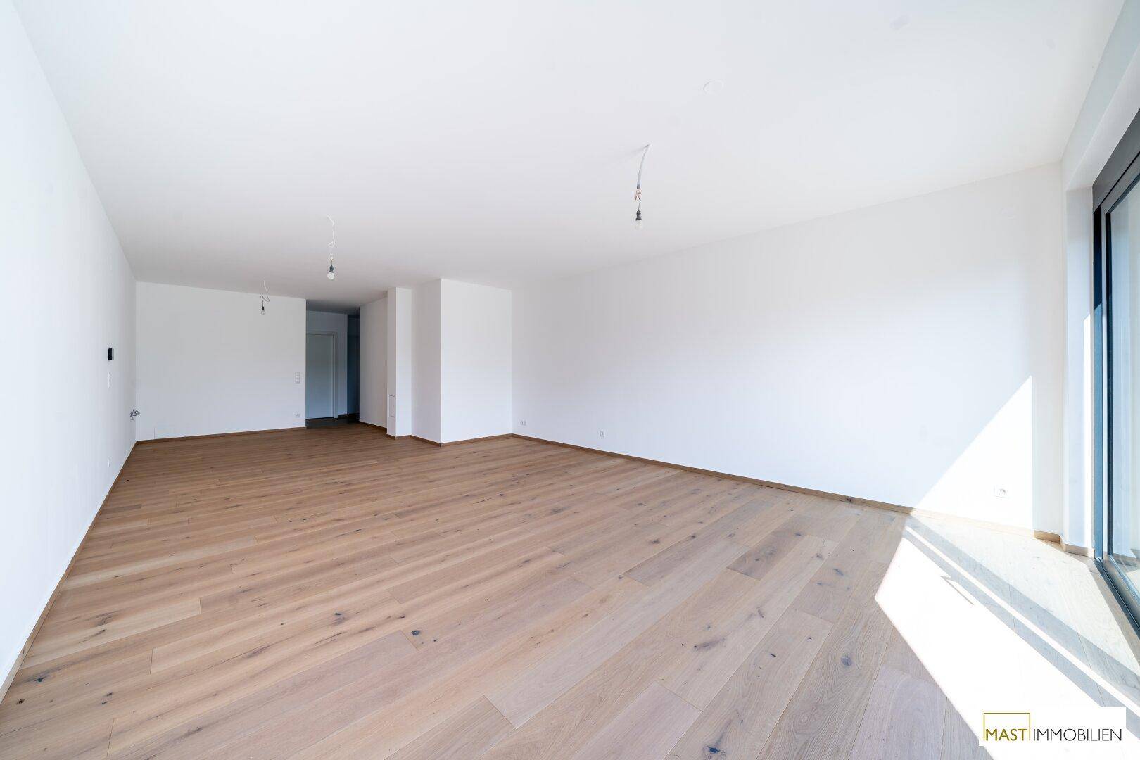Geräumiges, helles Zimmer mit Holzboden und weißen Wänden, bereit zur individuellen Gestaltung.