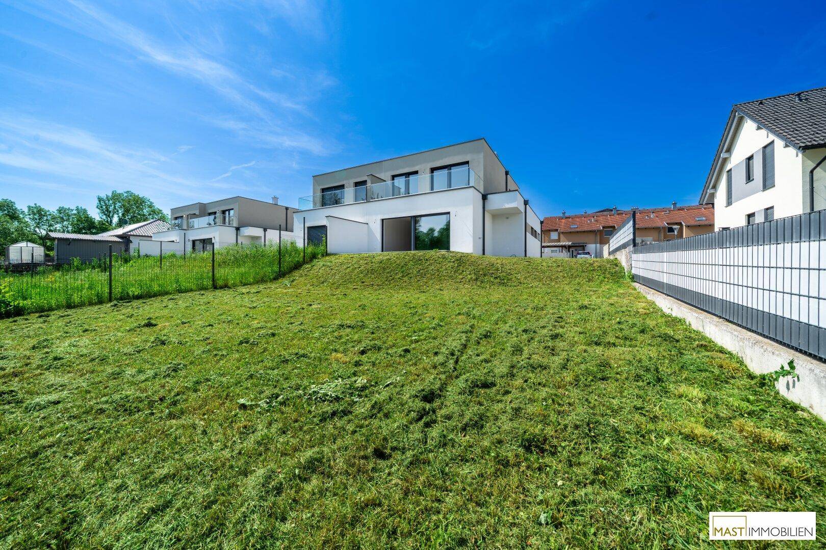 Großer, gepflegter Gartenbereich hinter dem modernen Haus mit viel Grünfläche.