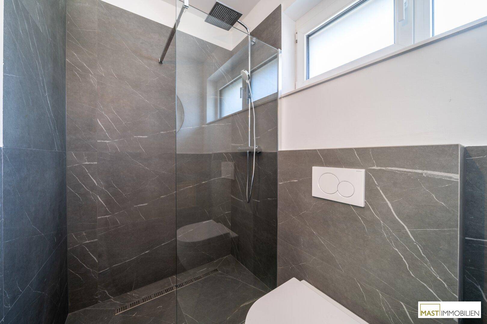 Elegante Duschkabine mit großformatigen Marmorfliesen, Regendusche und Fenster für Tageslicht.