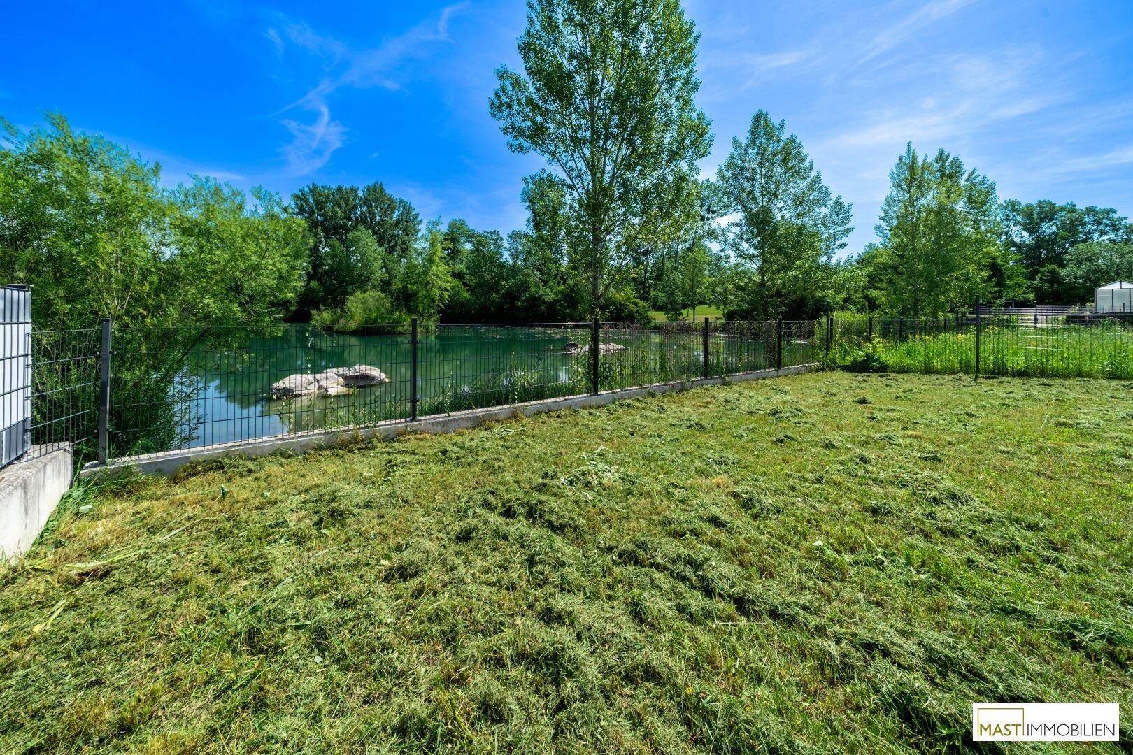 Weitläufiger Garten mit frischem Rasen und Blick auf den ruhigen See, ideal zum Entspannen.