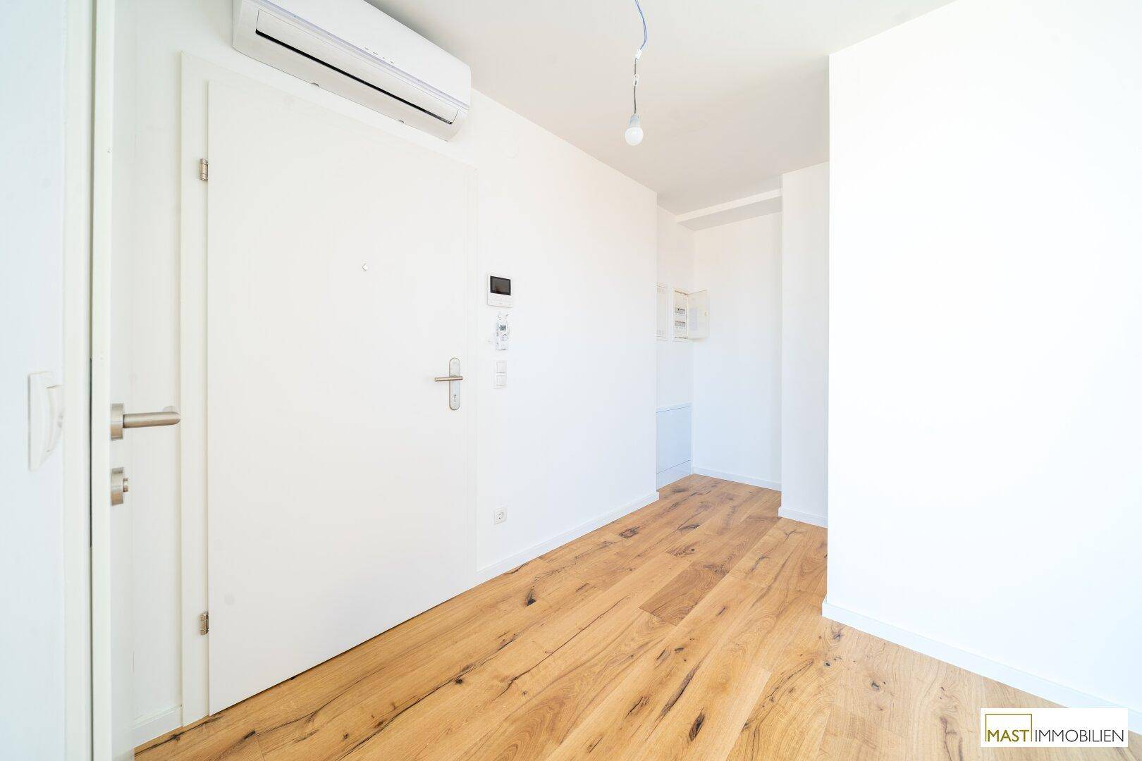 Geräumiger Flur mit Holzboden und Klimaanlage, ideal für den Empfang von Gästen oder als Übergangsbereich.