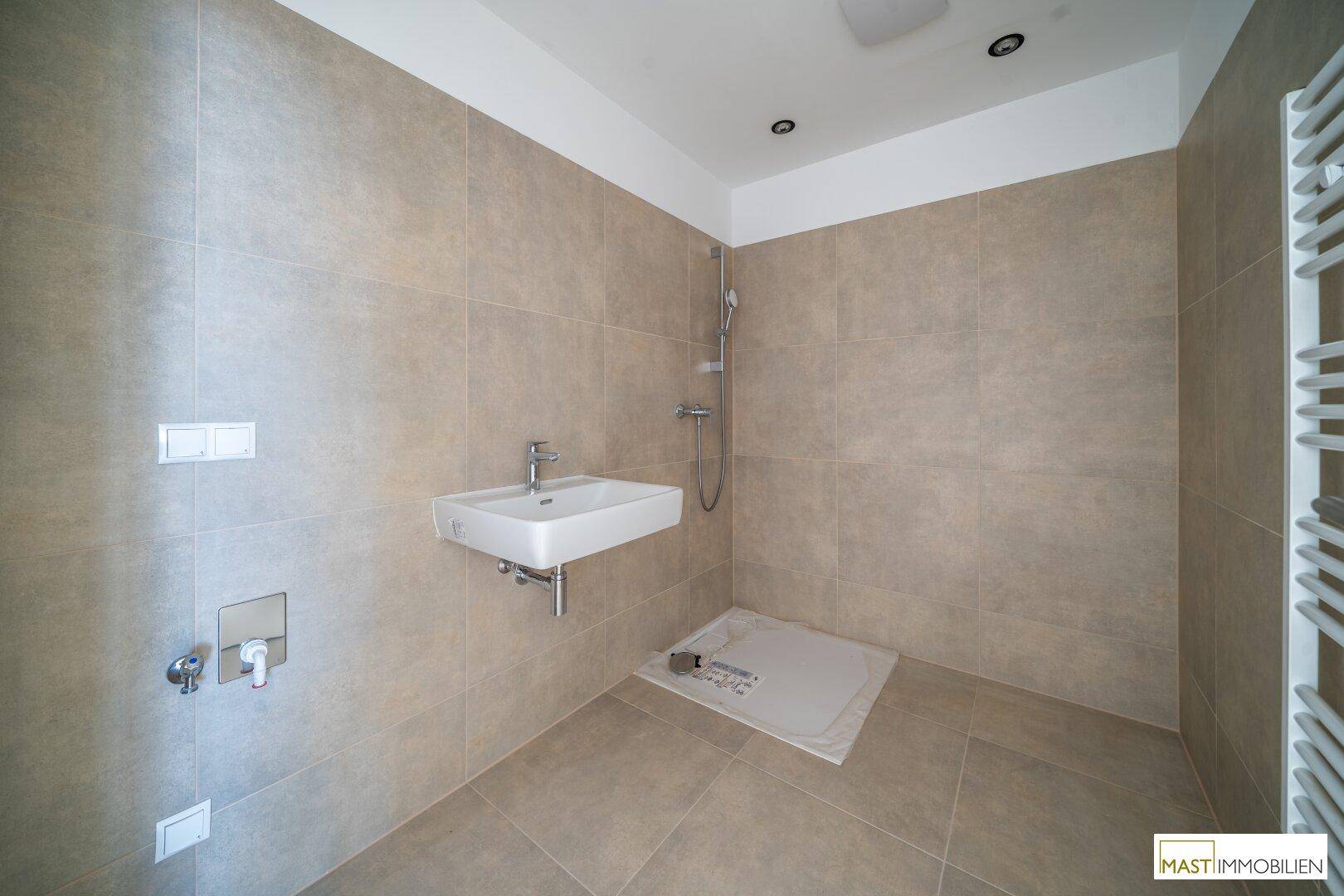 Modernes Badezimmer mit ebenerdiger Dusche, Einzelwaschbecken und Handtuchheizkörper, stilvoll und funktional.