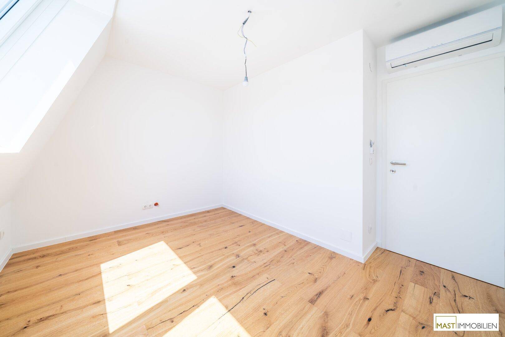Geräumiges Zimmer mit Holzboden, Dachfenster und Klimaanlage für angenehmes Klima, vielseitig einsetzbar.