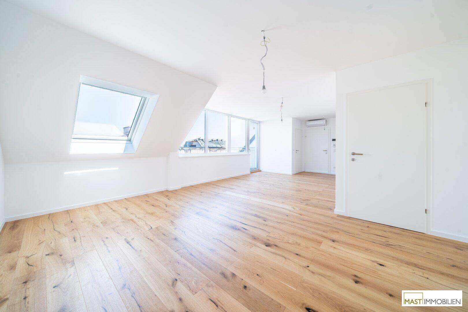 Heller Raum mit Holzboden, Dachfenstern, Balkonzugang und Klimaanlage, vielseitig nutzbar.