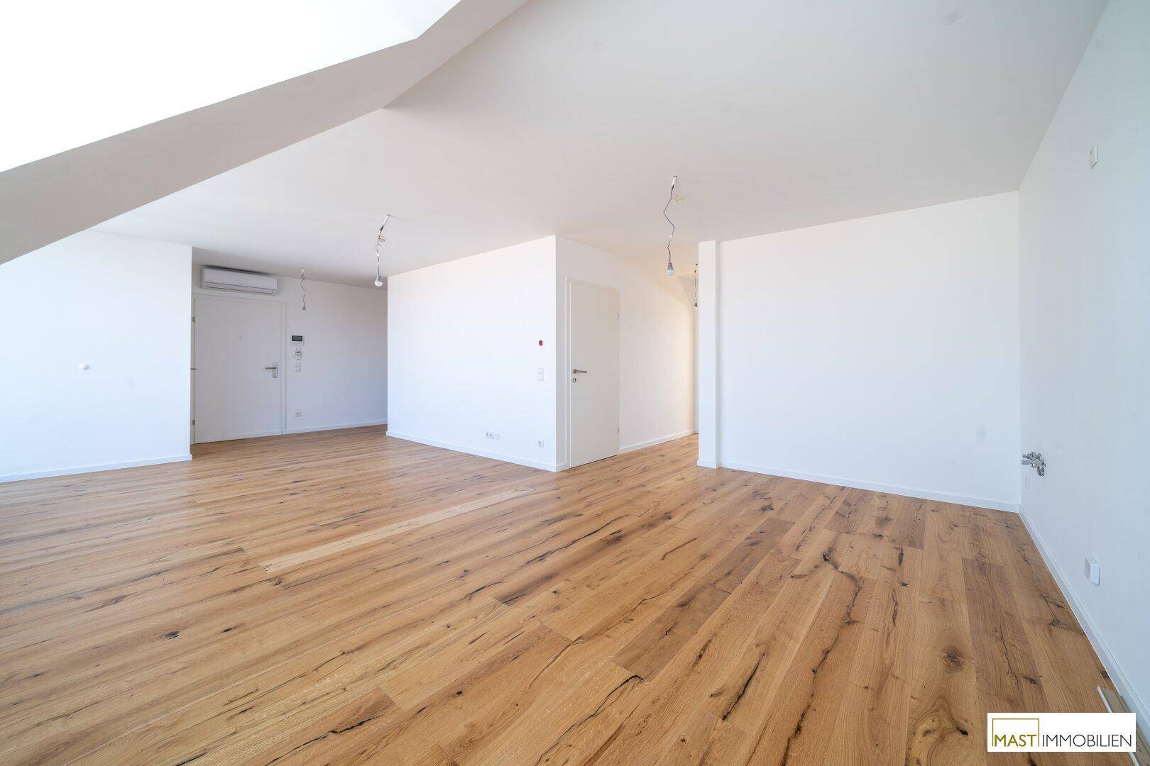 Geräumiger offener Bereich mit Holzboden und Klimaanlage, bereit zur individuellen Gestaltung und Nutzung.