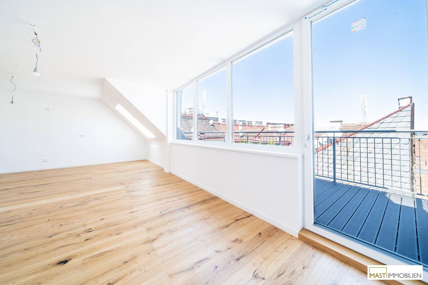 Heller Raum mit Holzboden, großen Fenstern und direktem Zugang zum Balkon, lichtdurchflutet.