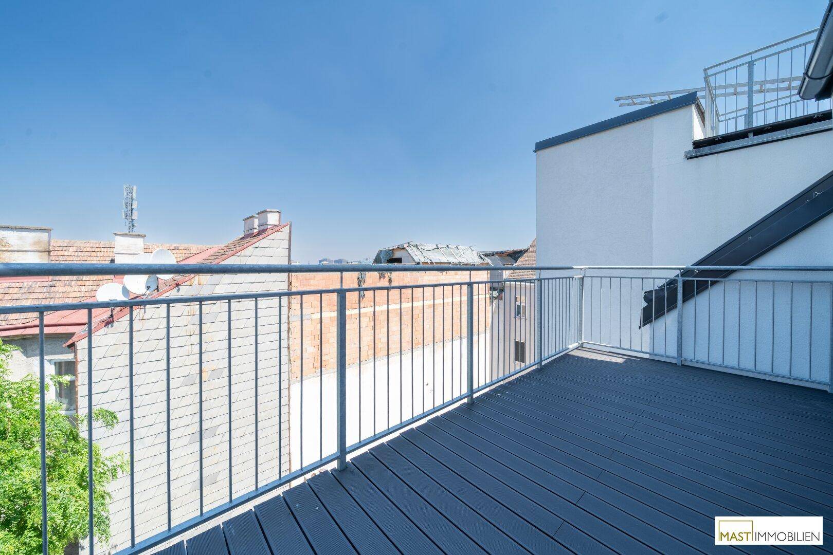 Sonniger Balkon mit Holzdielen und weitem Blick über die Stadt, perfekt für sonnige Tage.