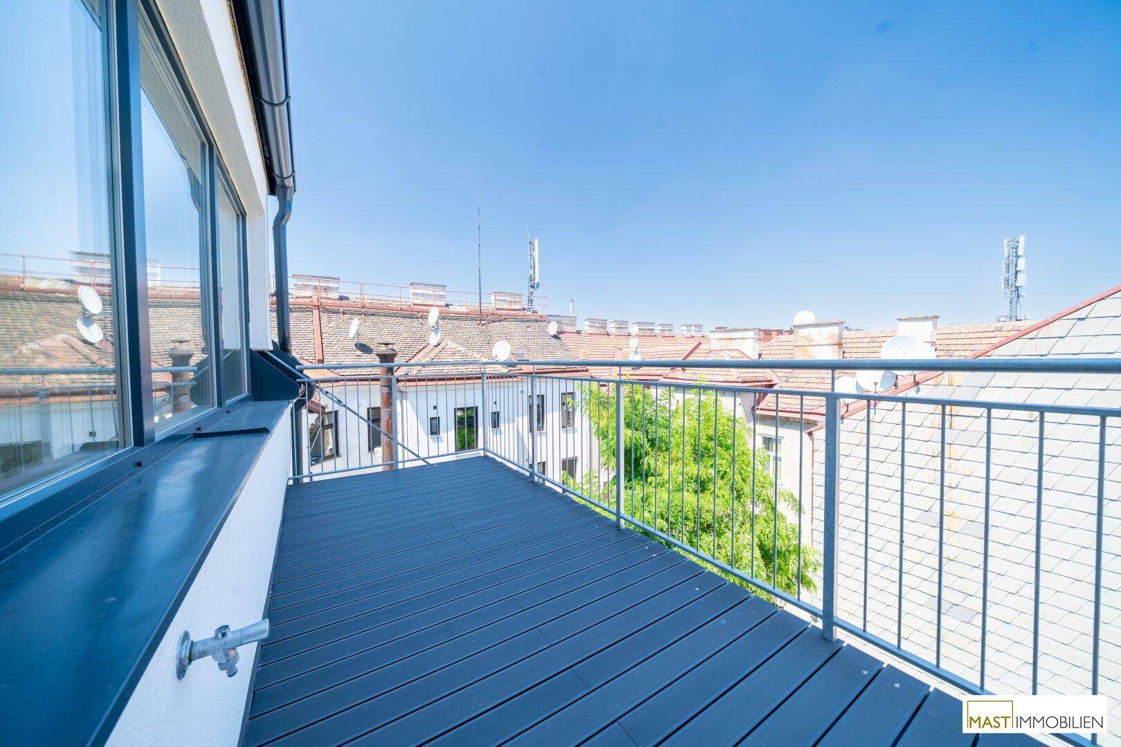 Heller Balkon mit Holzdielen und Blick auf die grüne Umgebung, bietet eine angenehme Atmosphäre.