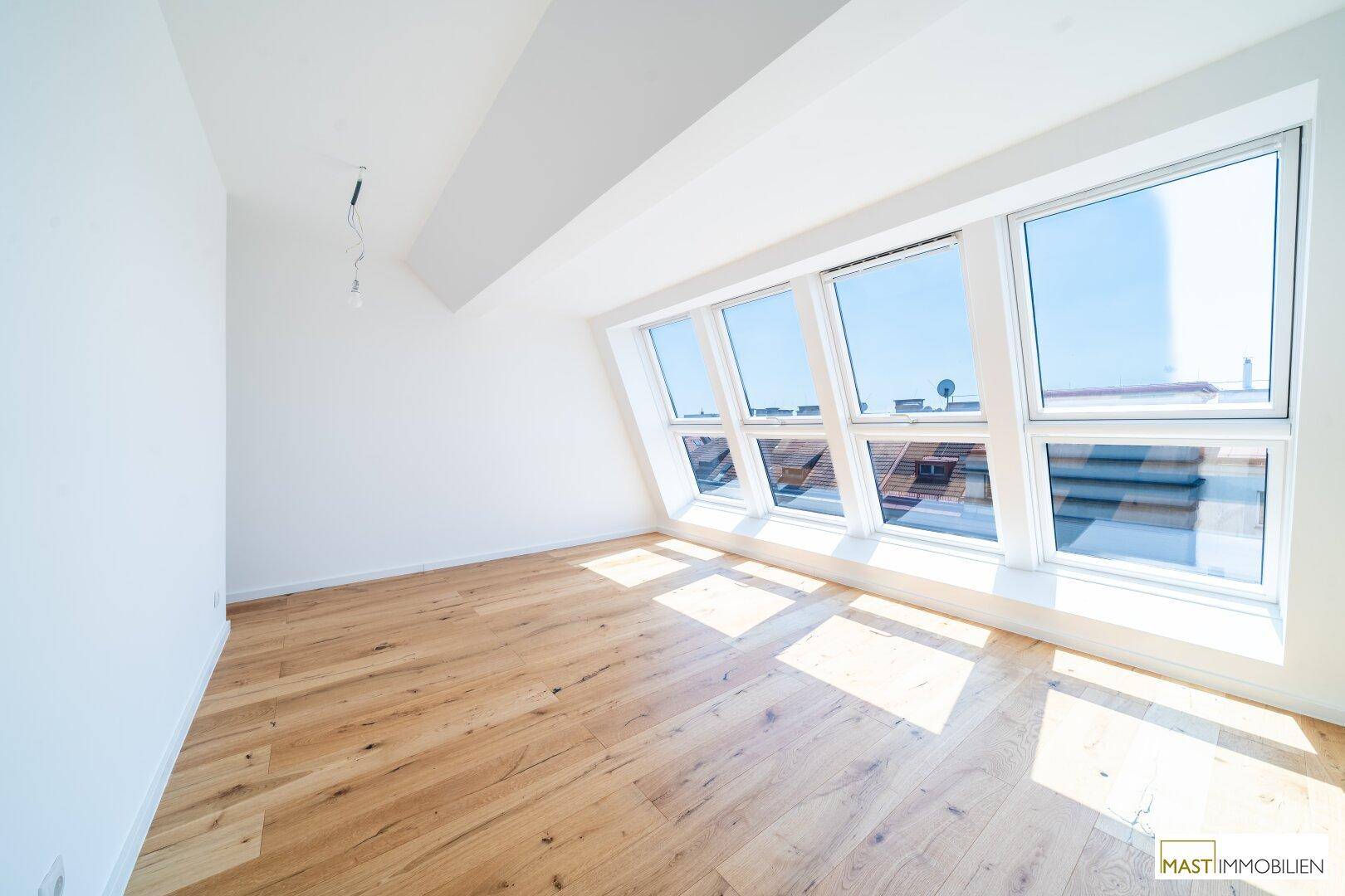 Geräumiges Zimmer mit Holzboden, großen Dachfenstern und viel Tageslicht, ideal als Schlafzimmer.