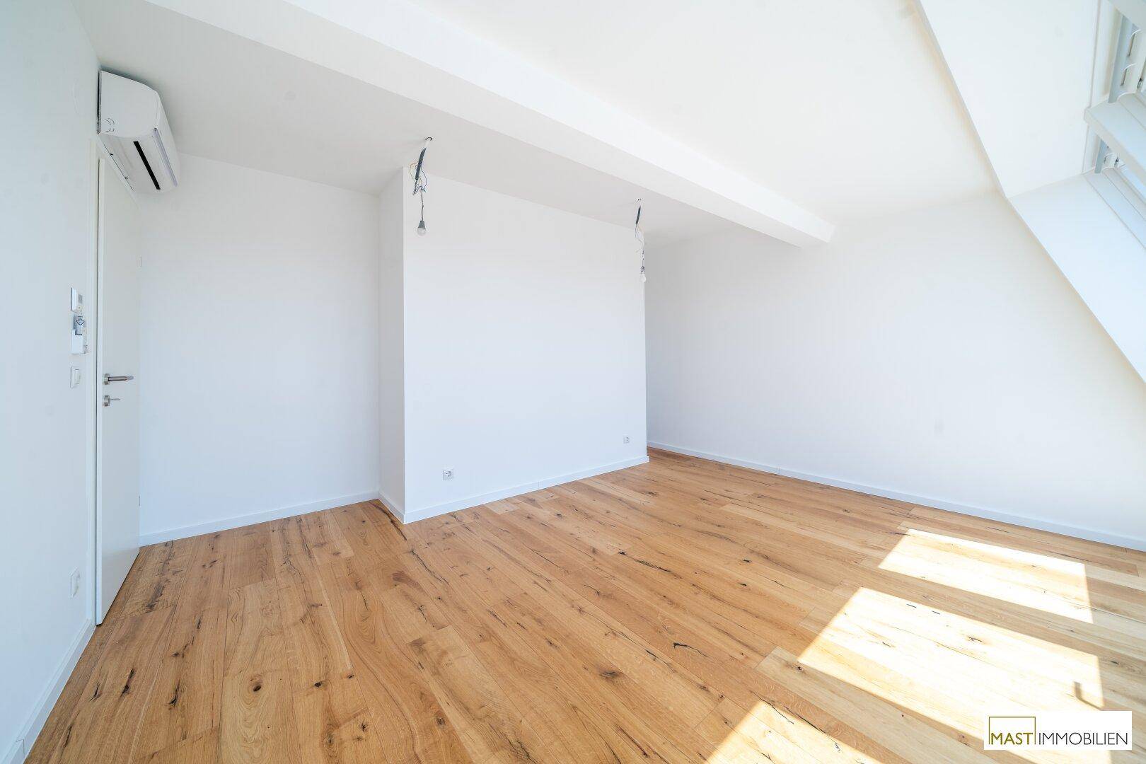 Geräumiger, heller Raum mit Holzboden und Klimaanlage, bereit für die Einrichtung.