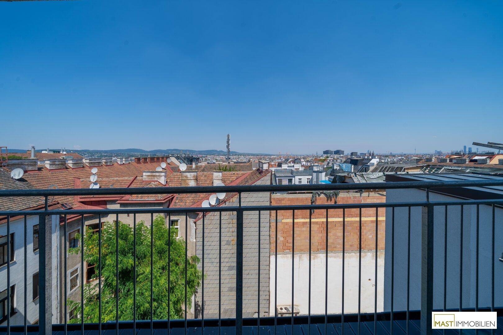 Weitläufiger Ausblick vom Balkon über die Dächer der Stadt bis zum Horizont.