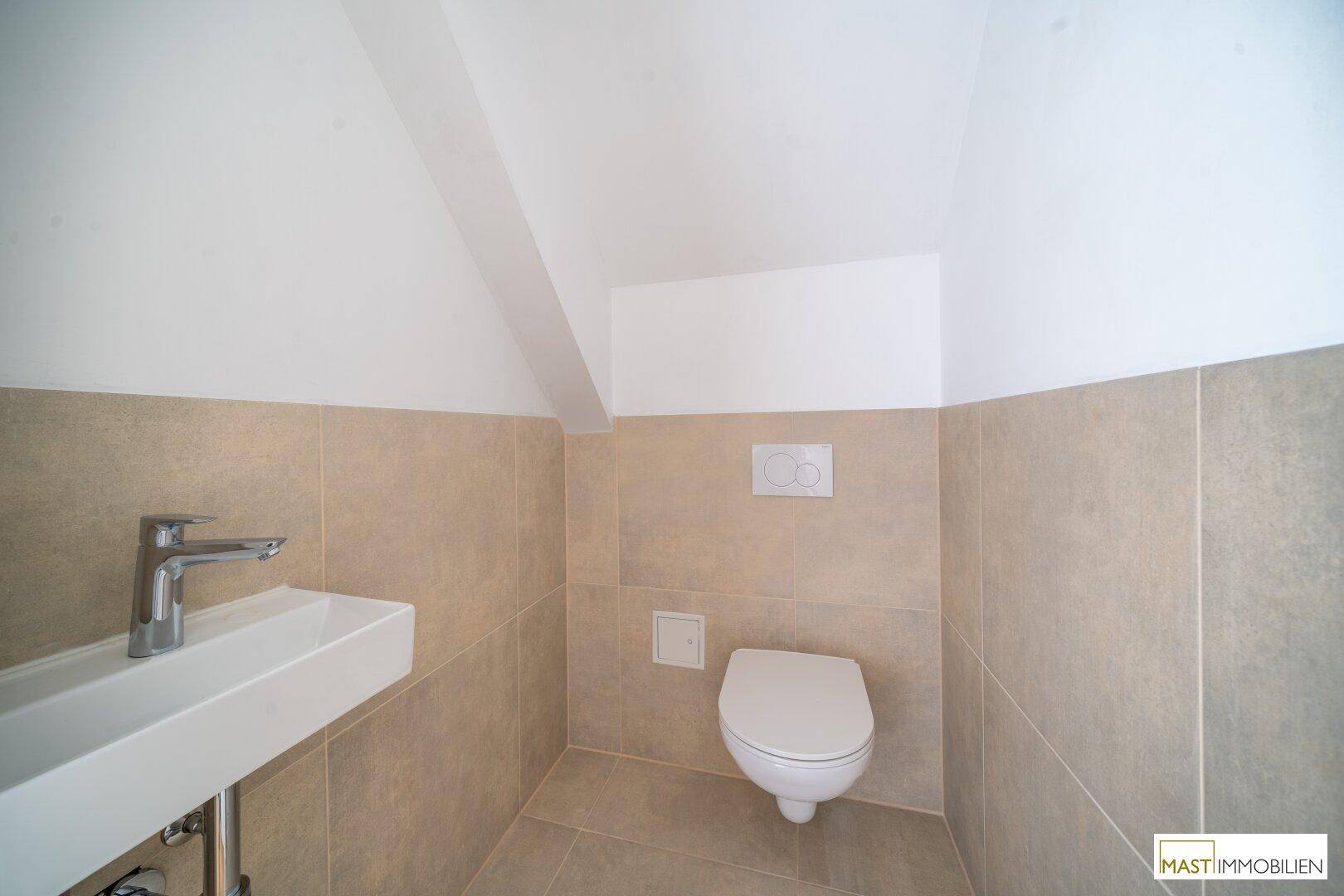 Kleines Gäste-WC im Dachgeschoss mit Wand-WC und modernem Waschbecken.