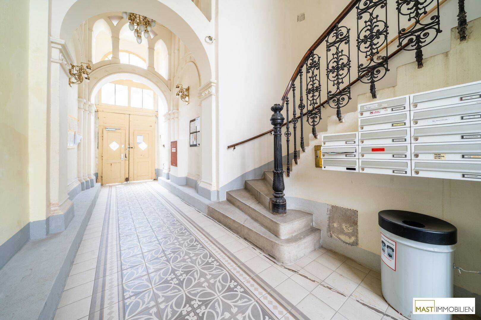 Historischer Eingangsbereich mit kunstvollen Fliesen, hohen Bögen und einer eleganten Treppe.