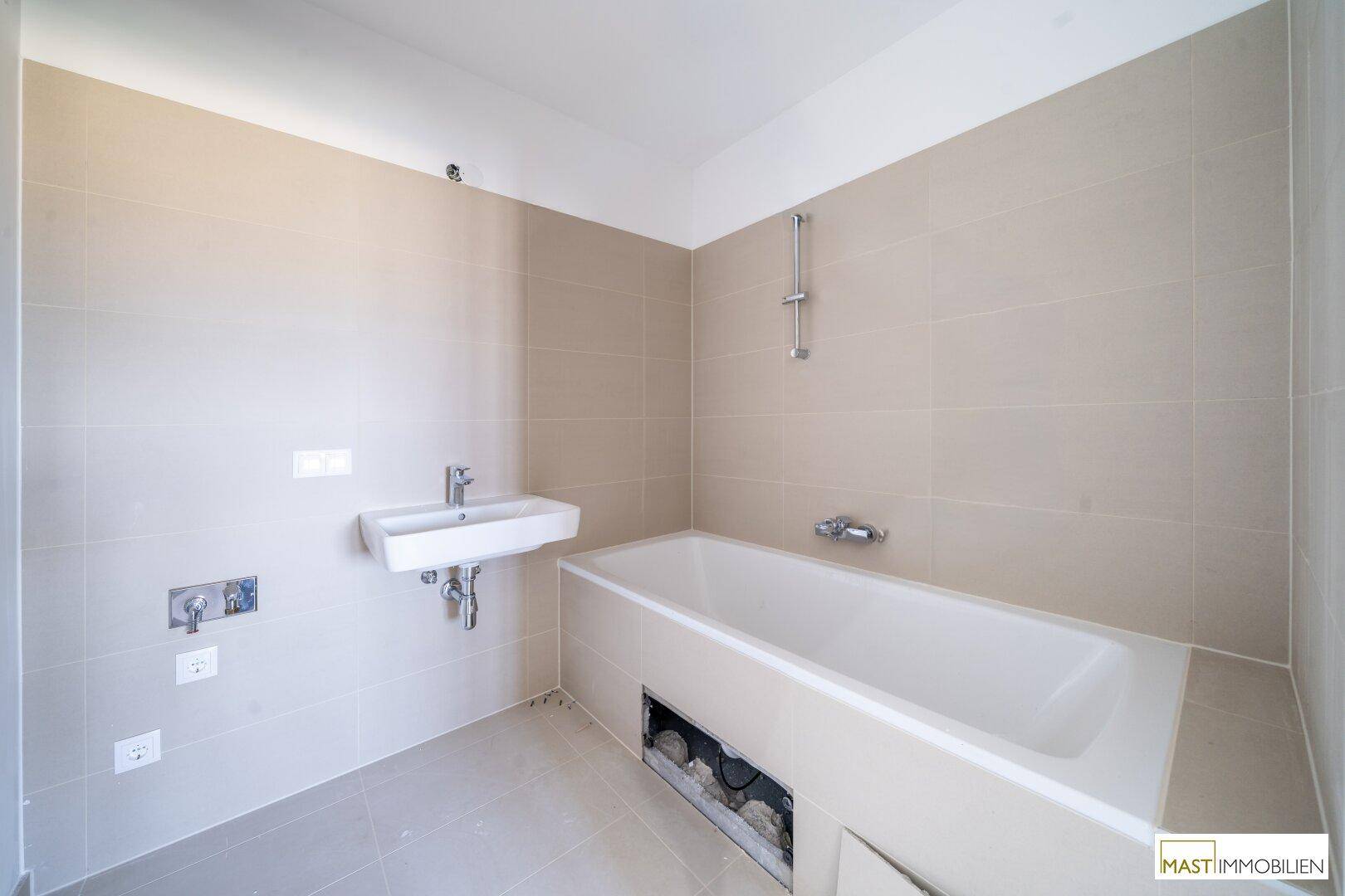 Helles Badezimmer mit Badewanne und Waschbecken, ausgestattet mit modernen Fliesen.