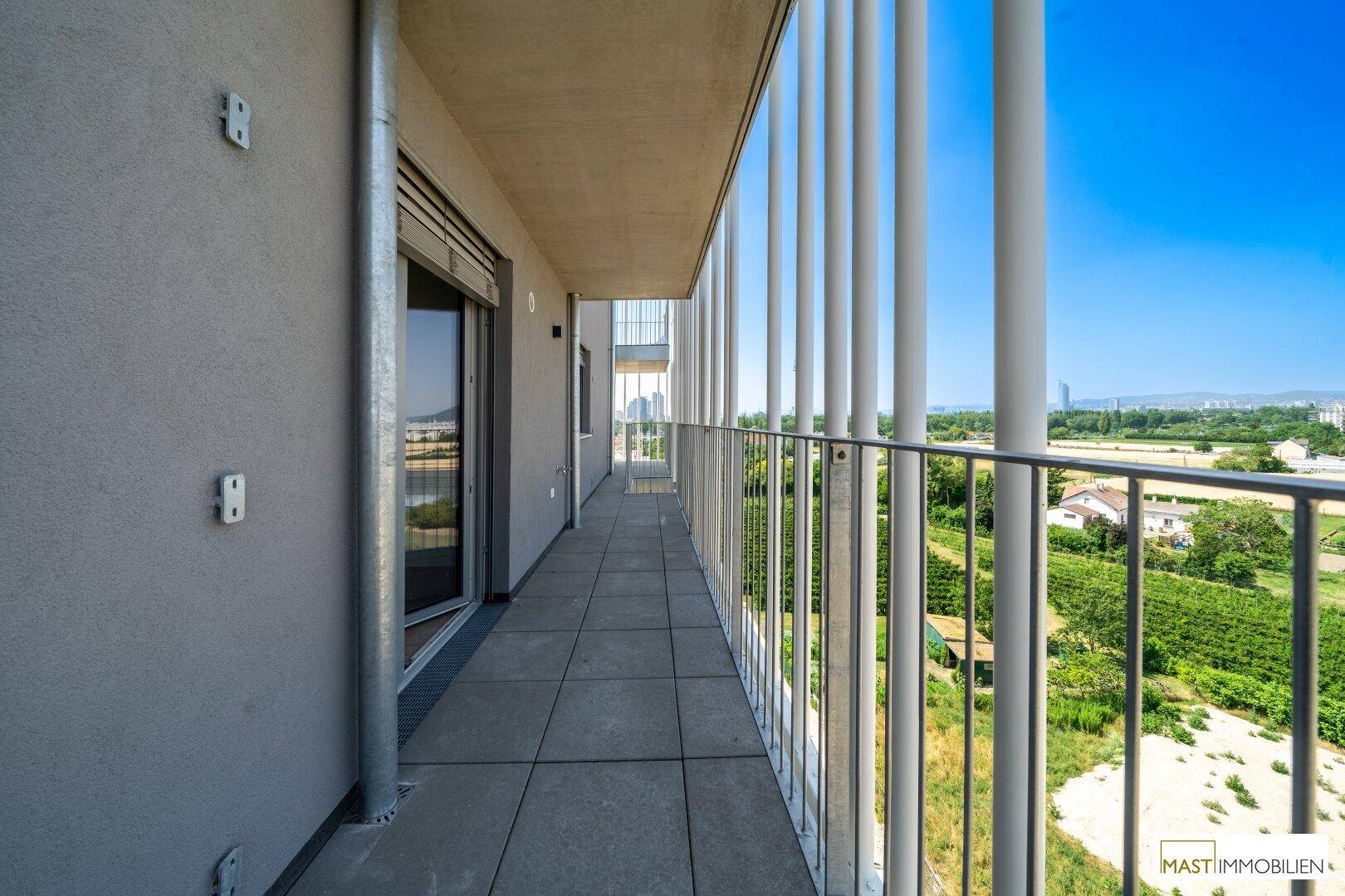 Langer Balkon mit Fliesenboden und weitem Blick über die Umgebung.