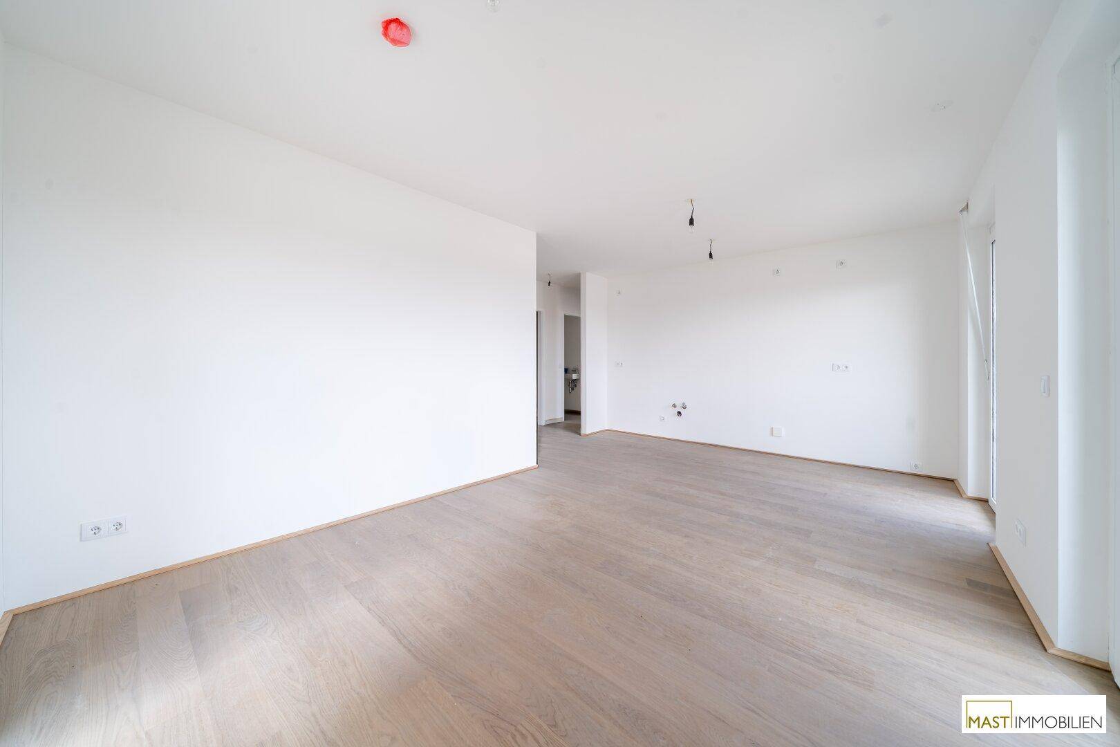 Heller, leerer Raum mit modernem Holzboden und weißen Wänden, bereit für die Einrichtung.