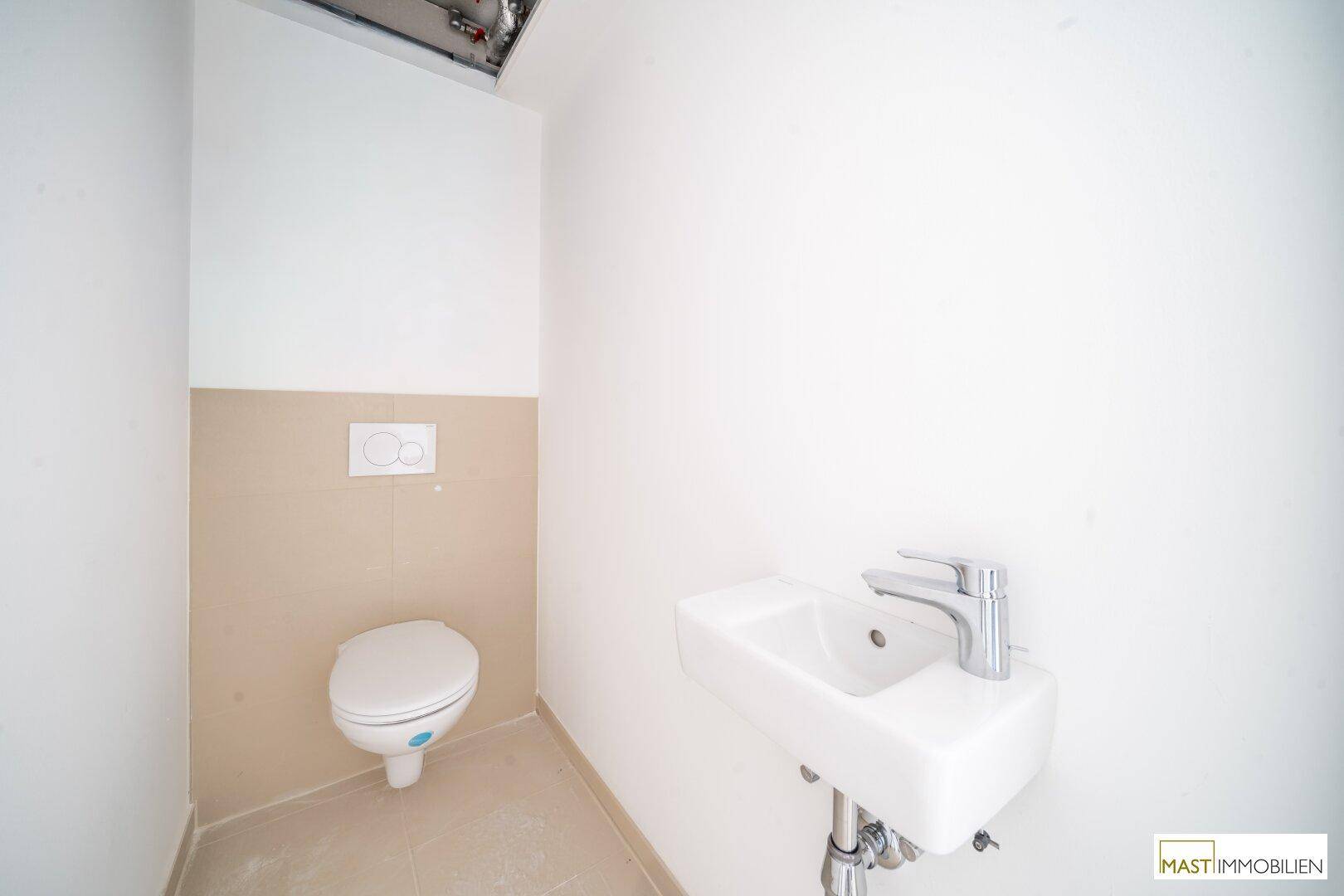 Modernes Gäste-WC mit wandhängender Toilette und kleinem Waschbecken in hellen Farbtönen.