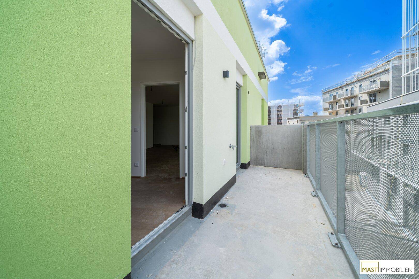 Geräumiger Balkon mit grüner Fassade und Blick auf die Umgebung und den Himmel.