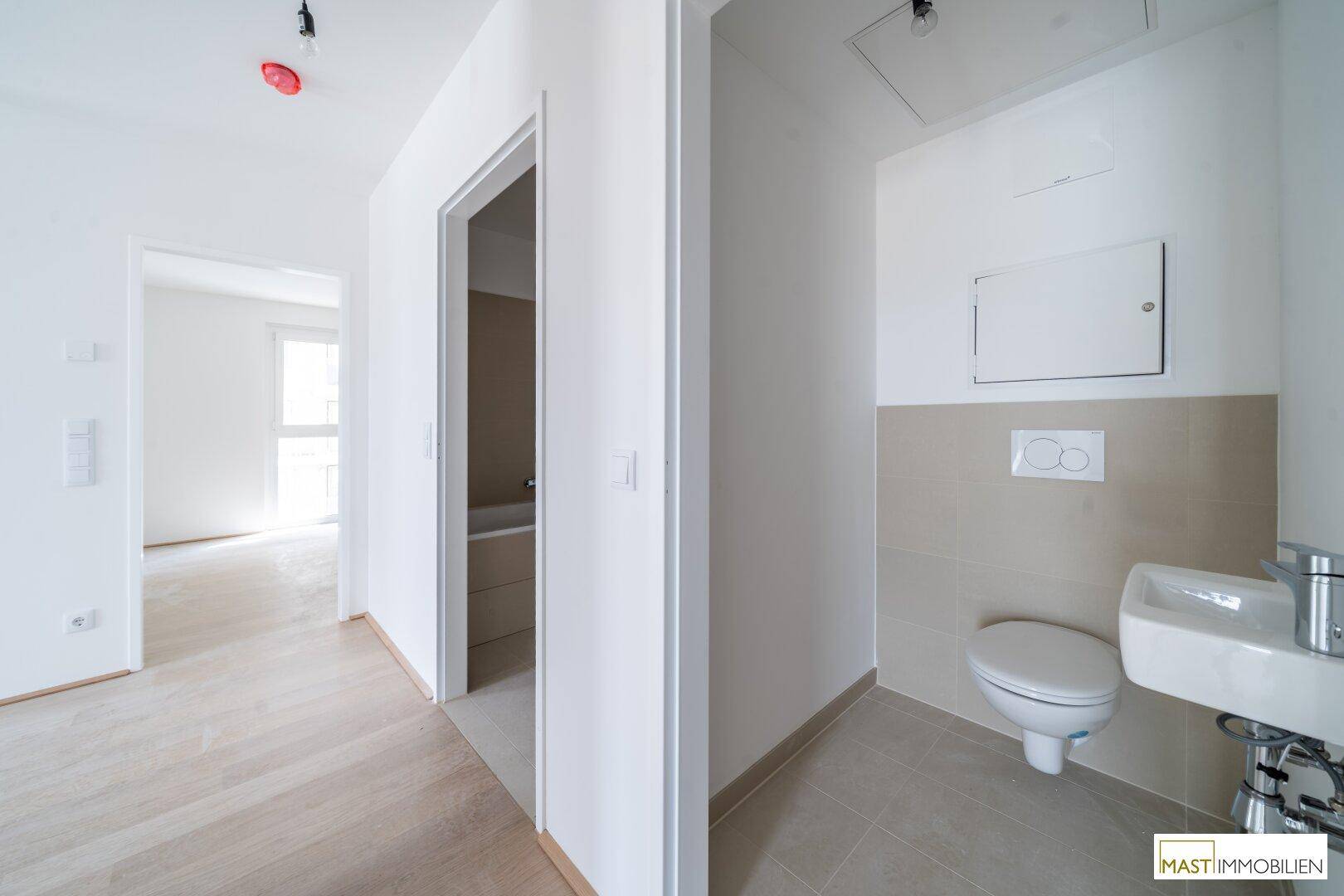 Modernes Gäste-WC mit Wand-WC und kleinem Waschbecken in neutralen Farbtönen.