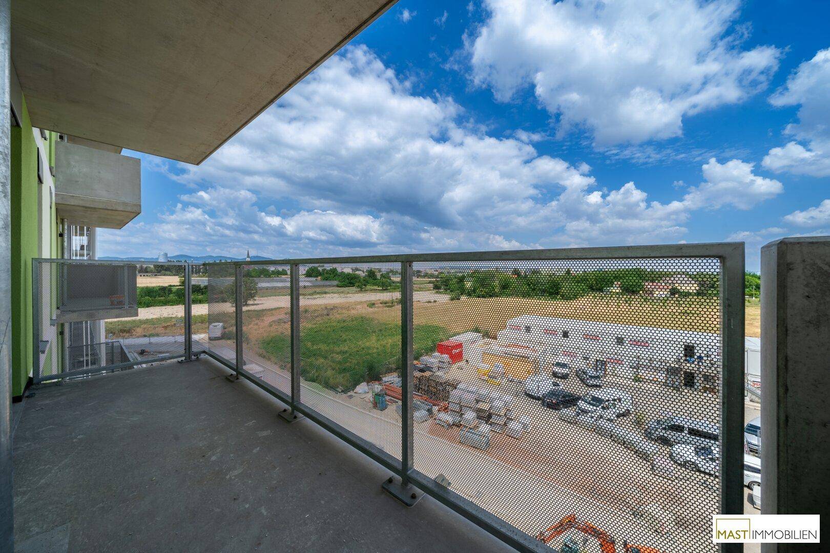 Geräumiger Balkon mit modernem Metallgeländer und weitem Blick über die grüne Umgebung.