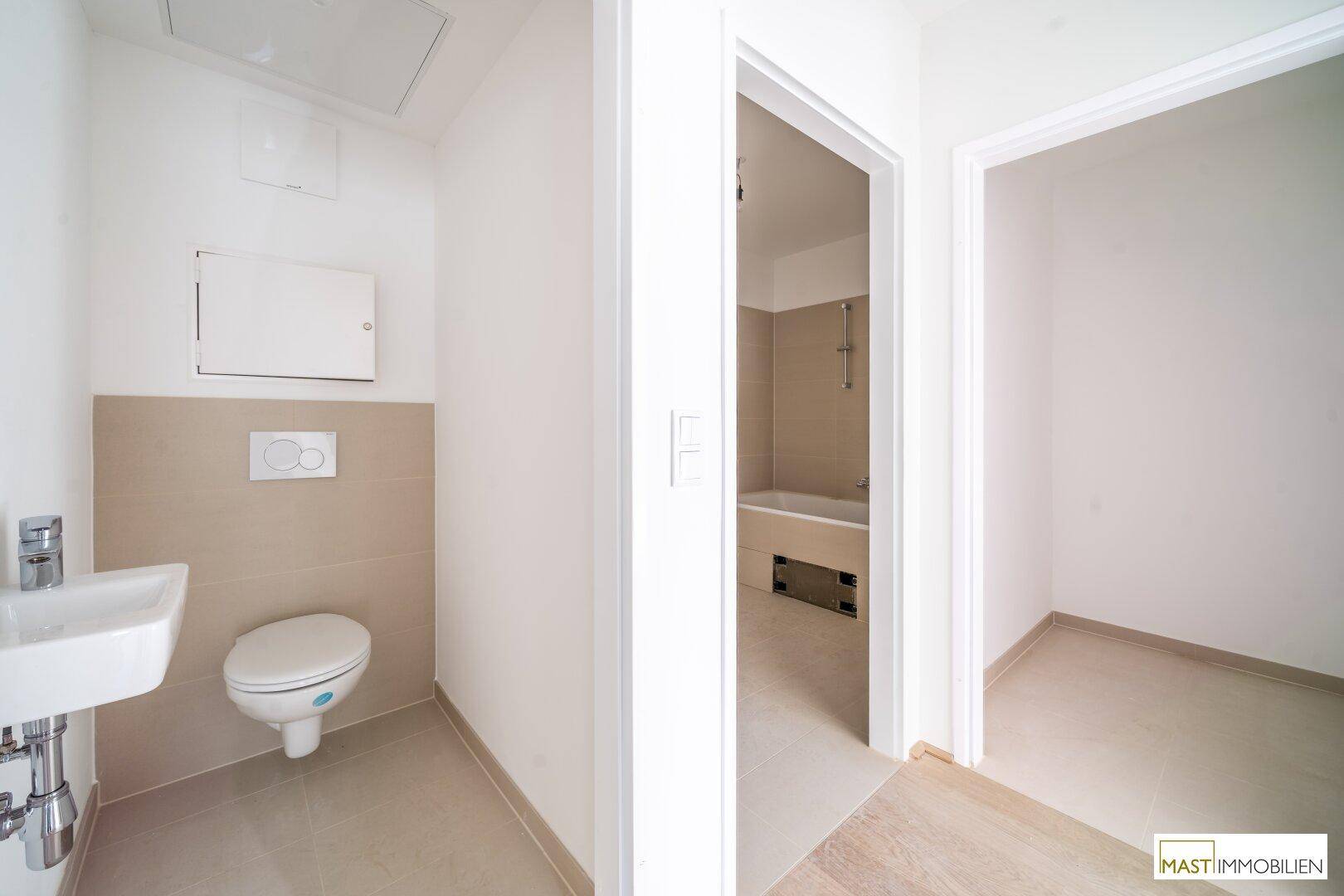 Moderner WC-Bereich mit Waschbecken und Blick in ein angrenzendes Badezimmer.