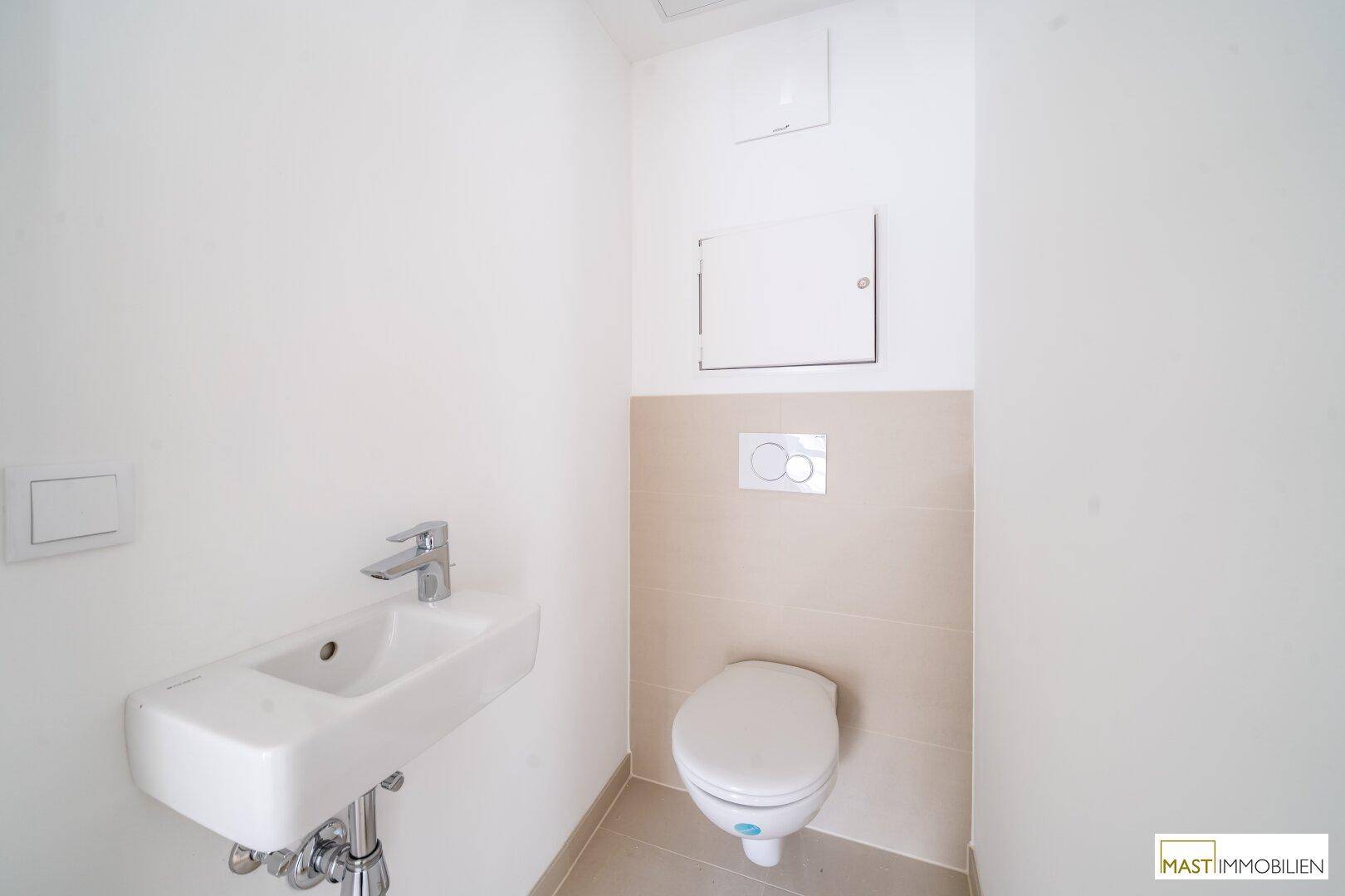 Separates WC mit wandhängender Toilette und kleinem Waschbecken in modernem Design.