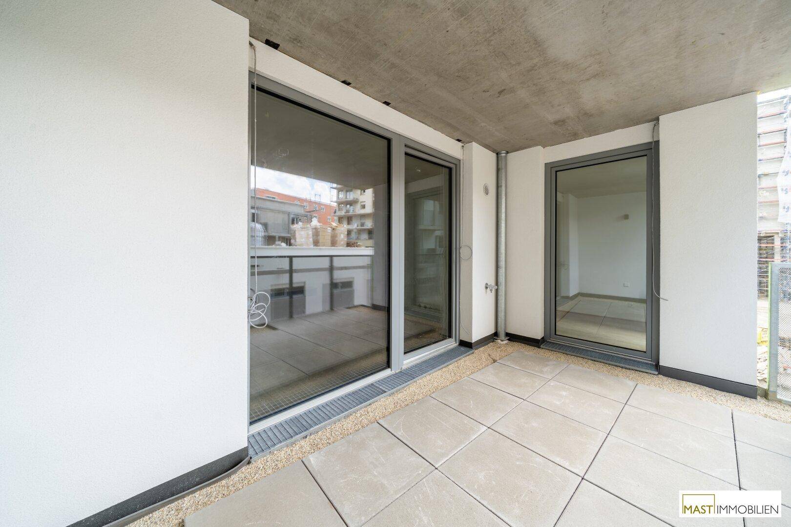 Geräumiger Balkon mit Fliesenboden und Blick auf die umliegenden Gebäude.