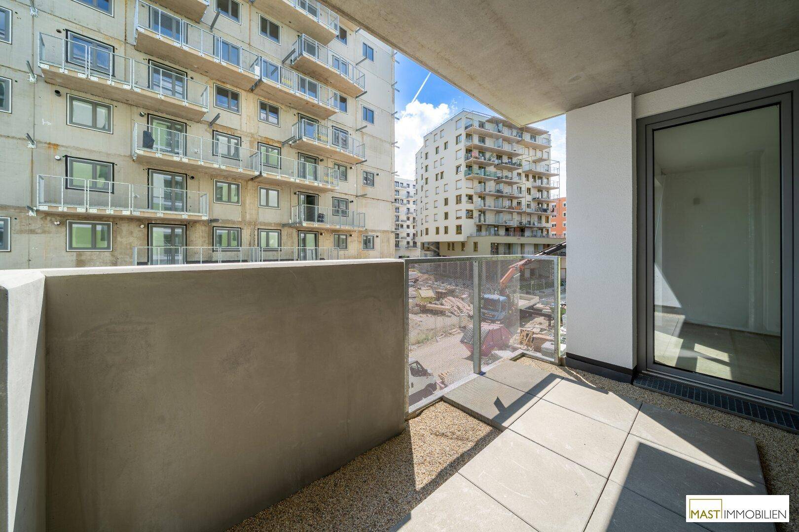 Geräumiger Balkon mit Blick auf moderne Wohngebäude und eine aktive Baustelle in der Nachbarschaft.