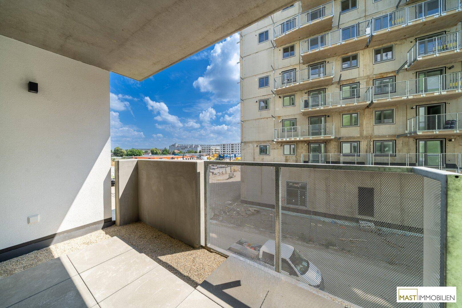 Weitläufiger Balkon mit Panoramablick auf die städtische Umgebung und weitere Neubauten.