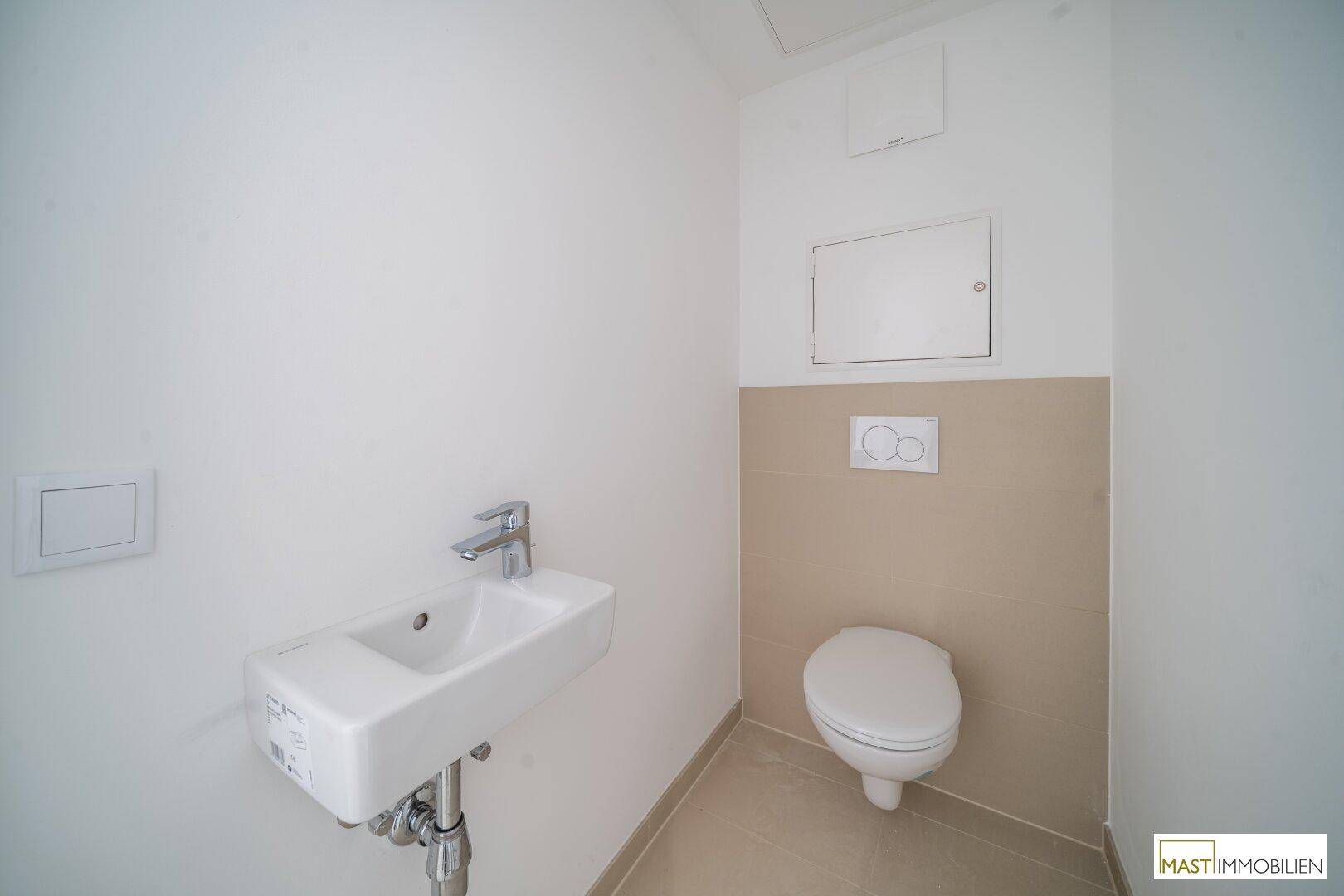 Funktionales Gäste-WC mit wandhängender Toilette und kleinem Handwaschbecken.