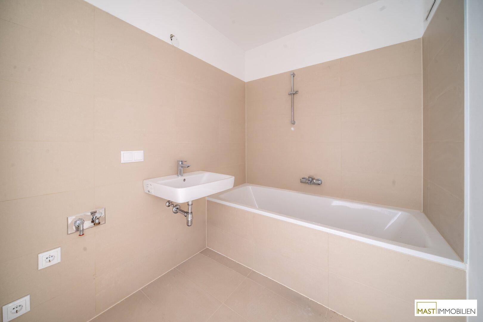 Modernes Badezimmer mit beigefarbenen Fliesen, Badewanne und einem einzelnen Waschbecken.