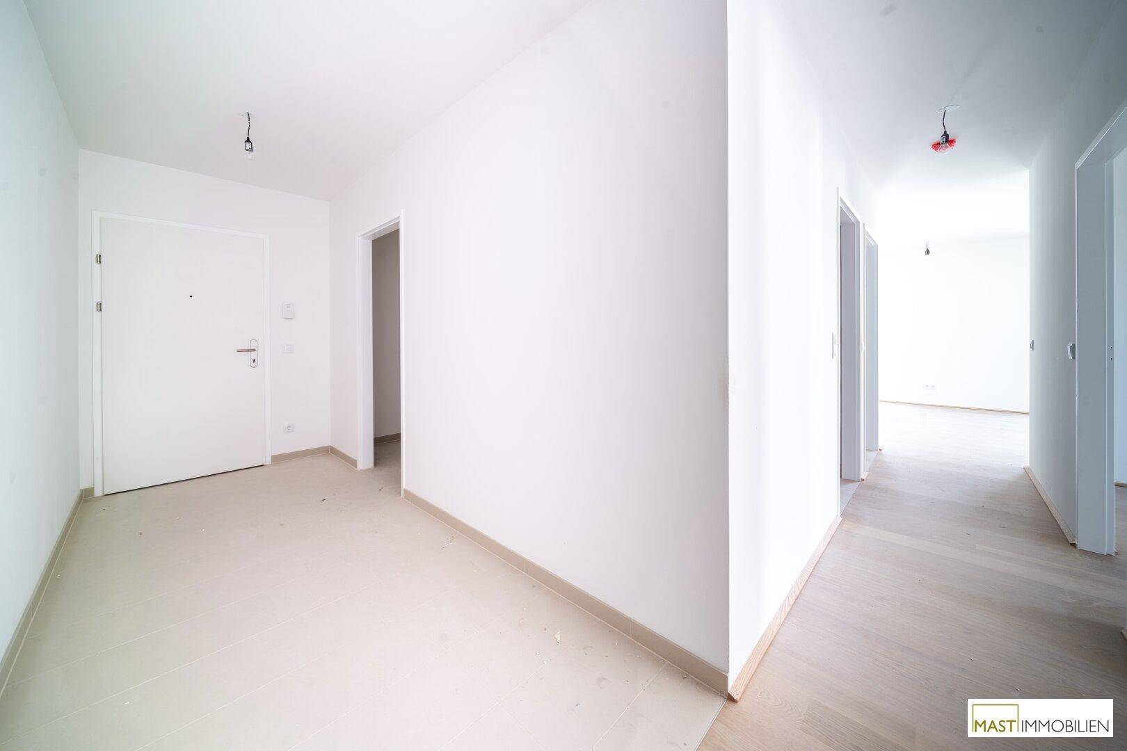 Geräumiger Flur mit mehreren Türen und Übergang zu hellem Holzfußboden, wirkt modern und offen.