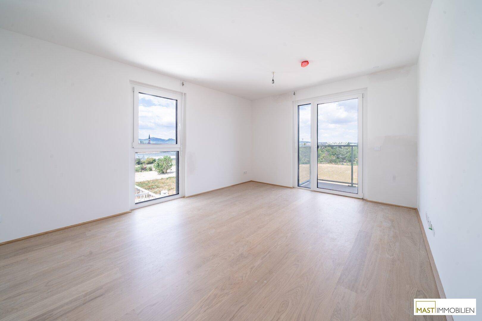 Geräumiges, unmöbliertes Zimmer mit hellem Boden und Zugang zu einem Balkon, ideal für individuelle Gestaltung.