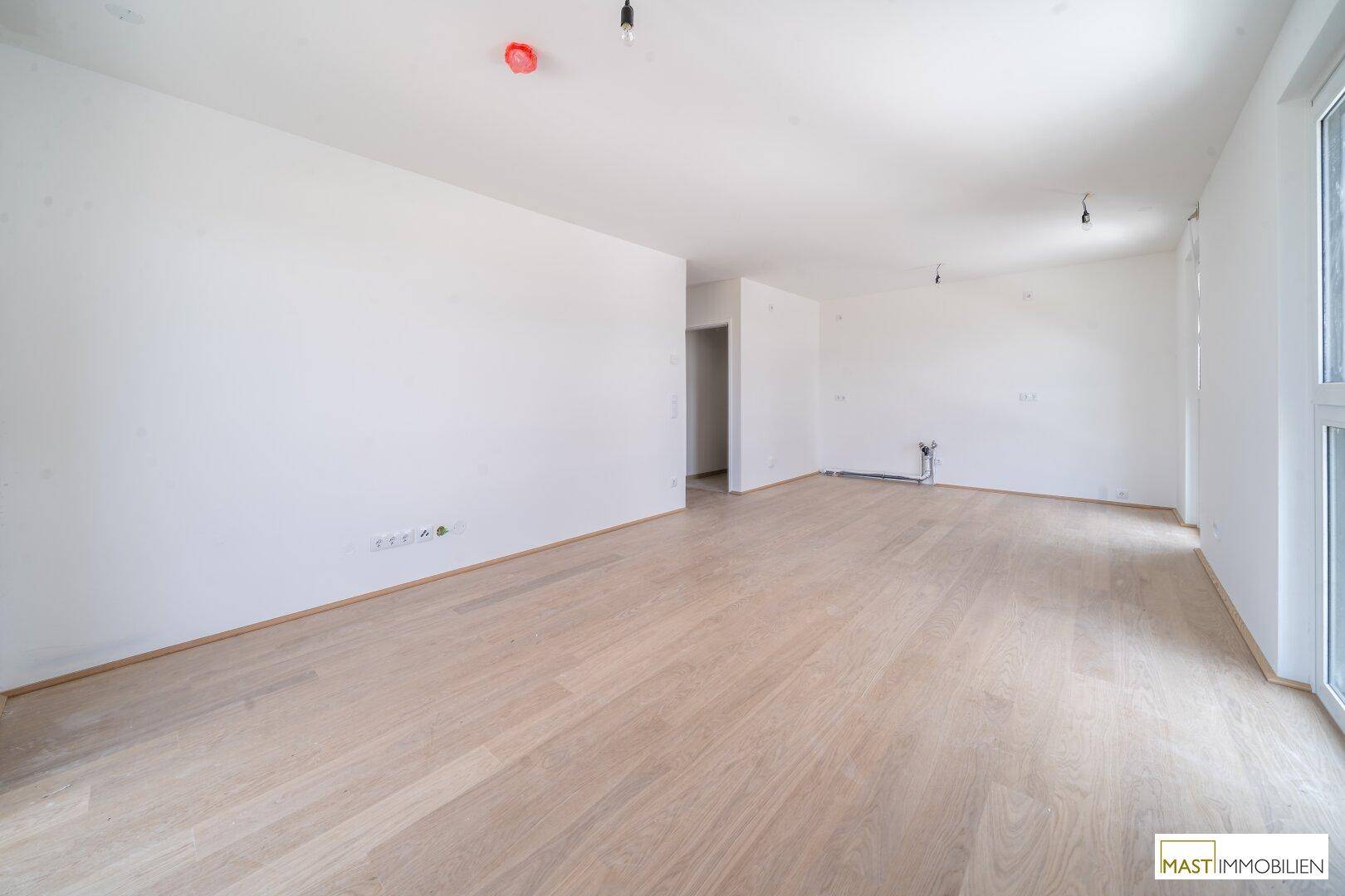 Heller, unmöblierter Raum mit weiß gestrichenen Wänden und modernem Laminatboden, bereit zum Einzug.