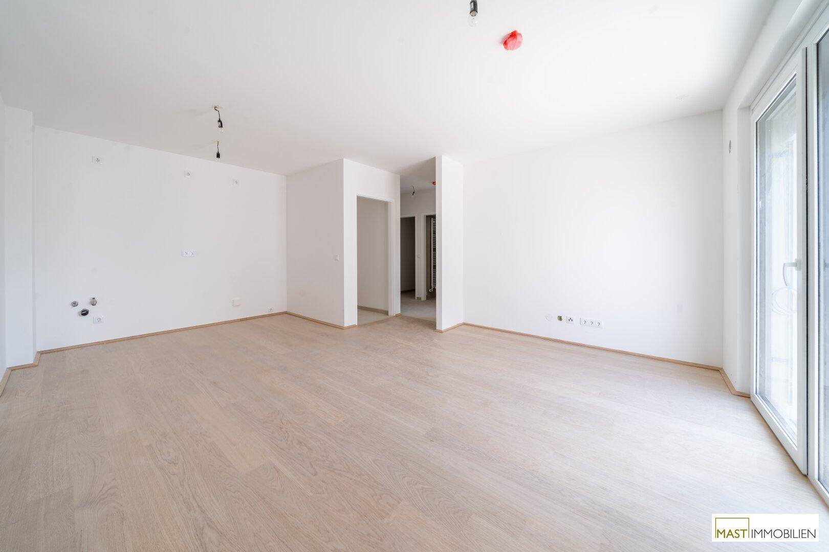 Geräumiges, leeres Wohnzimmer mit hellen Wänden und Holzboden, bereit zum Einzug.
