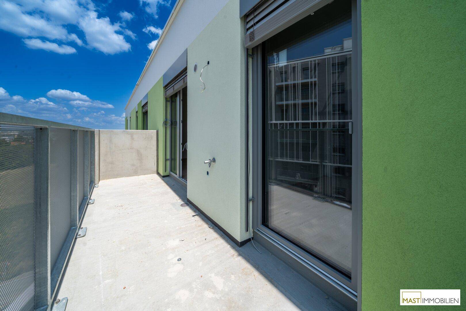 Langer Balkon mit grüner Fassade und großen Fenstern, bietet einen weiten Ausblick.