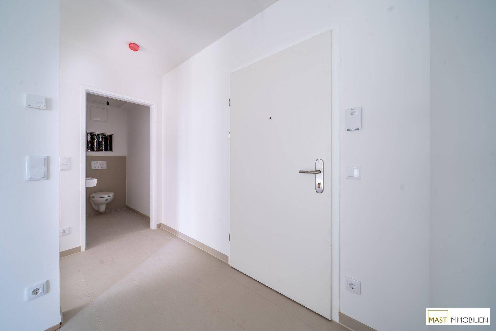 Eingangsbereich mit heller Tür und Zugang zu einem separaten WC, modern und funktional.