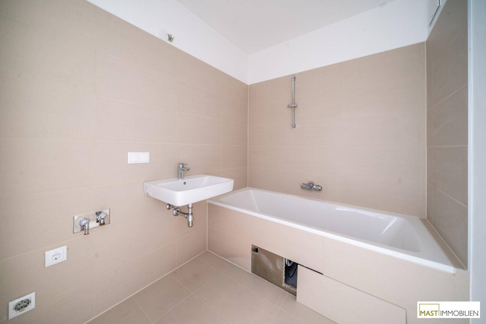Modernes Badezimmer mit Badewanne, Waschbecken und hellen Fliesen, bereit zur Nutzung.