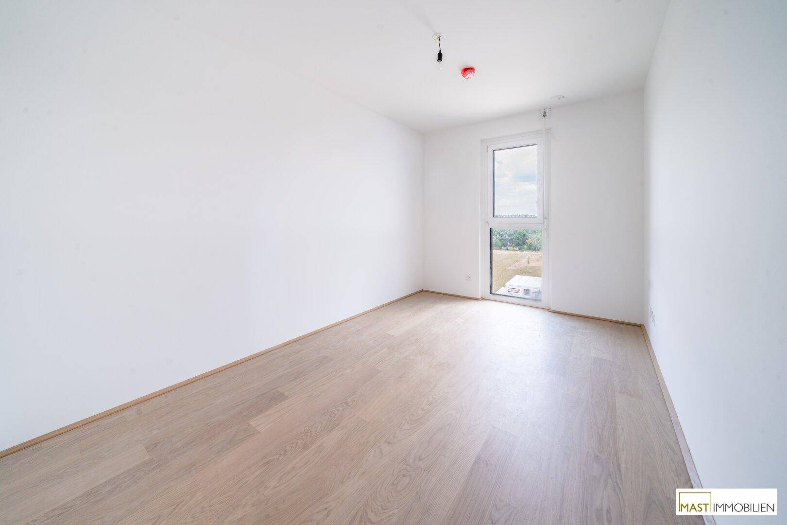 Modernes Schlafzimmer mit weiß gestrichenen Wänden und hellem Holzboden, bietet Zugang zu einem Außenbereich.