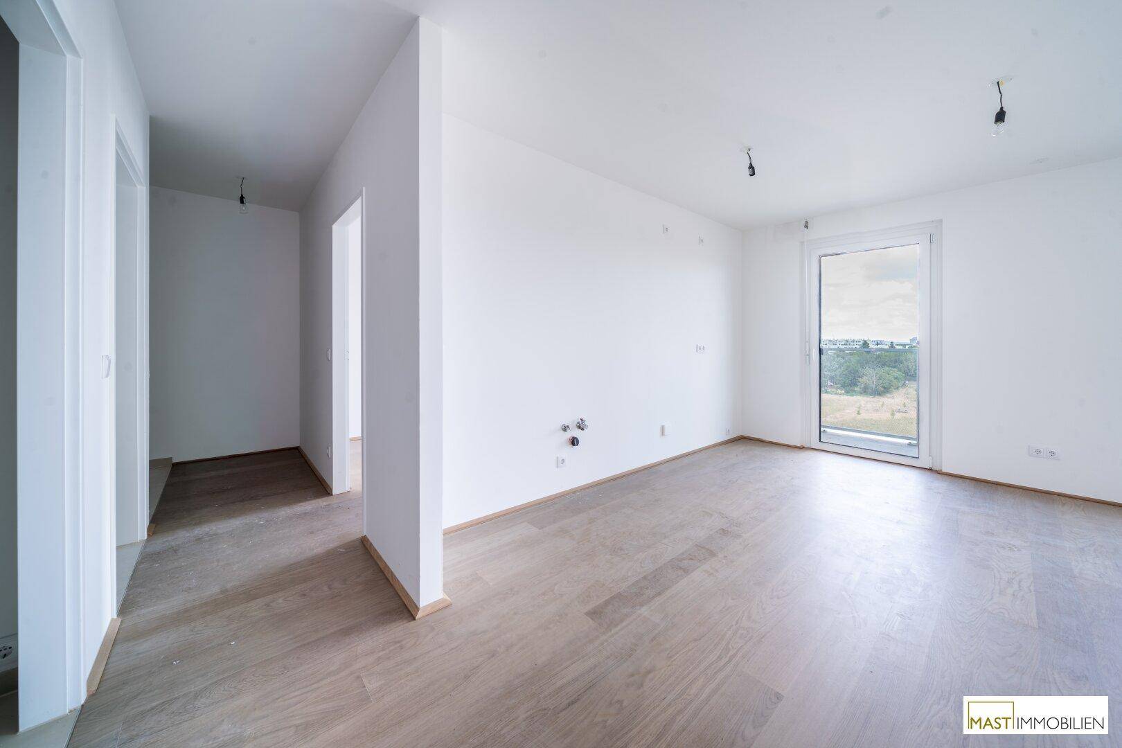 Heller Raum mit Holzboden und Zugang zu einem Flur, ideal für individuelle Gestaltungsmöglichkeiten.