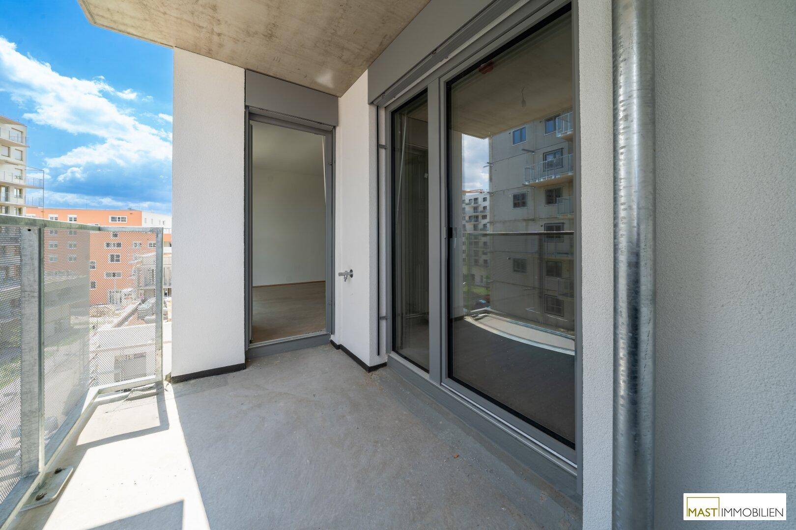 Heller Balkon mit Metallgeländer und Blick auf die umliegenden Neubauten, ideal für entspannte Stunden.