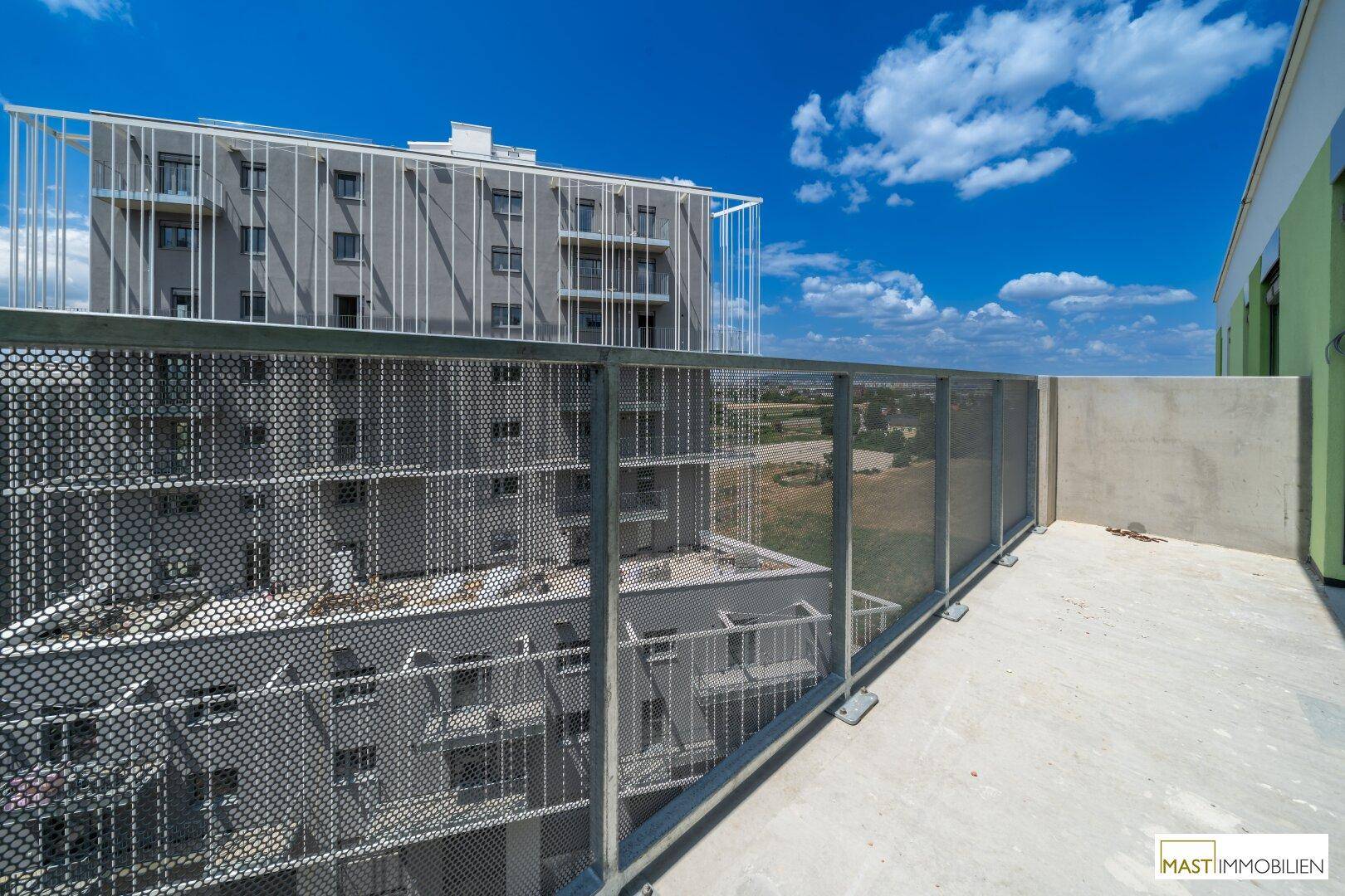 Weitblick vom Balkon auf moderne Wohngebäude unter einem klaren blauen Himmel.